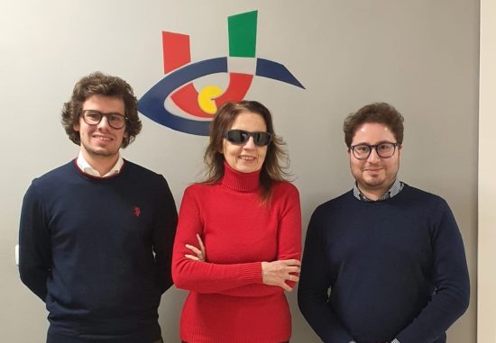 Nella foto la presidente Uici, Gigliola Chiappini, in abito rosso, sorride e posa insieme ad Andrea Traini e Francesco Corimbi presidente e vicepresidente di 'Innova'. Sulla parete chiara alle loro spalle è disegnato il logo dell'Uici