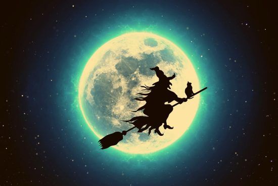 Una befana vola sulla sua scopa davanti alla Luna, luminosa, in una notte stallata