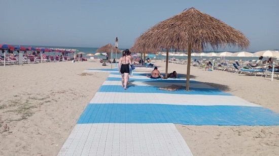 Persone che camminano sulla passerella della spiaggia accessibile